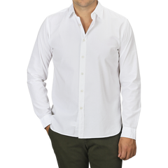 A person wearing a slim fit White Cotton Twill Legacy Shirt by Xacus and dark green pants stands with one hand in their pocket. The individual's face is not visible.