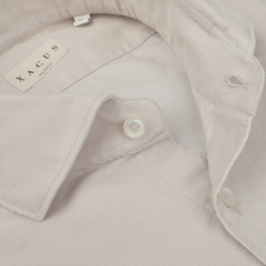 Close-up of the Xacus Light Beige Cotton Corduroy Tailor Fit Shirt with a collar, buttons, and a visible brand label. This casual shirt is crafted from pure cotton corduroy, offering both comfort and style.