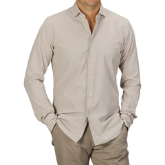 A man wearing a Xacus Light Beige Cotton Corduroy Tailor Fit Shirt, hands in pockets. The shirt is untucked with the top button open, and he's standing against a plain, light background.