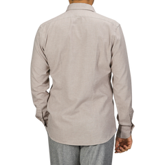 A person wearing a long-sleeved, light beige cotton flannel tailor fit shirt from Xacus and gray pants, photographed from the back against a gray background.