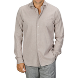 A man in a Light Beige Cotton Flannel Tailor Fit Shirt by Xacus and grey pants stands with one hand in his pocket against a plain background.