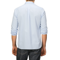 Someone wearing a Light Blue Cotton Twill Legacy Shirt by Xacus and dark jeans is standing with their back to the camera.