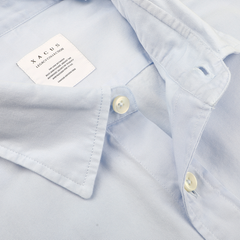 Close-up of the Light Blue Cotton Twill Legacy Shirt by Xacus, showcasing pure cotton fabric with an open collar and visible buttons. A label inside the collar reads "Xacus" with additional text in smaller font.