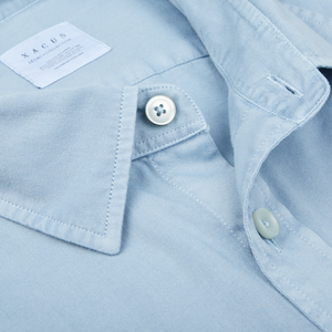 Close-up of a Xacus Light Blue Washed Cotton Twill Legacy Shirt focusing on the collar and button details with a visible brand label.