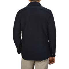 A person is shown from the back, wearing a Navy Blue Boiled Wool Jersey Overshirt with a collar and buttoned cuffs from Xacus. The slim-fit shirt is paired seamlessly with light-colored pants.