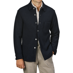 A person wearing the Xacus Navy Blue Boiled Wool Jersey Overshirt over a light shirt and beige pants. The slim fit jacket features a front pocket and silver buttons.