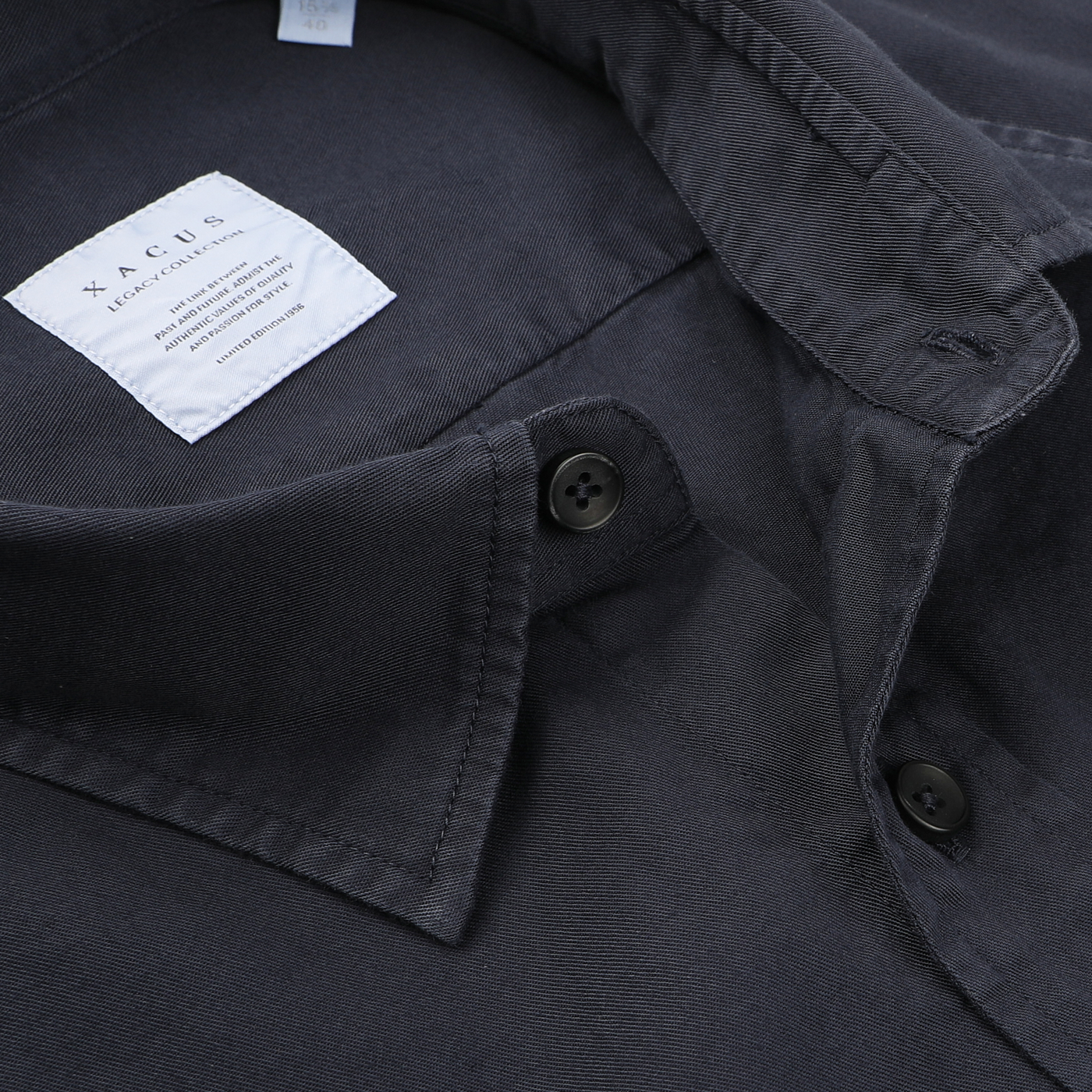 Close-up of a pure cotton twill navy blue collared shirt by Xacus, featuring black buttons and a visible label inside the collar, radiating the easy charm of a casual shirt.