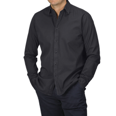 A person wearing the Navy Blue Cotton Twill Legacy Shirt by Xacus, paired with dark pants and hands in pockets, stands against a gray background.