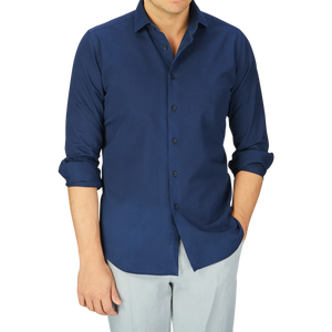 A man wearing a casual Xacus Navy Blue Cotton Twill Tailor Fit Shirt and light gray pants.