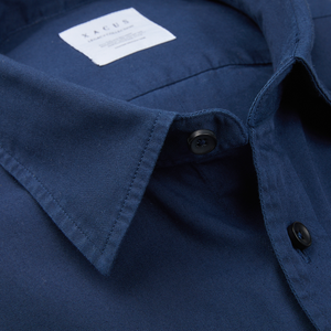 Close-up of a Xacus navy washed cotton twill legacy shirt with a visible brand label on the collar.