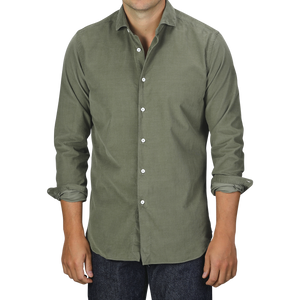 A person wearing an Olive Green Cotton Corduroy Tailor Fit Shirt by Xacus with rolled-up sleeves and dark jeans stands against a plain background.