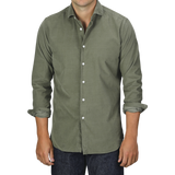 A person wearing an Olive Green Cotton Corduroy Tailor Fit Shirt by Xacus with rolled-up sleeves and dark jeans stands against a plain background.