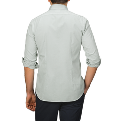 A person stands with their back to the camera, wearing a Sage Green Cotton Twill Tailor Fit Shirt by Xacus and dark pants.