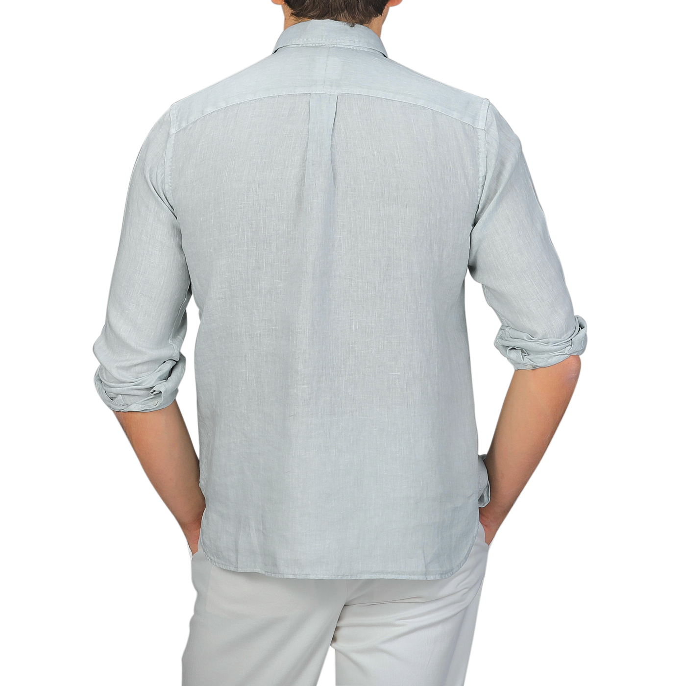 A person in a sage green, washed linen Legacy Shirt by Xacus is wearing white pants and seen from the back.