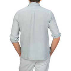 A person in a sage green, washed linen Legacy Shirt by Xacus is wearing white pants and seen from the back.