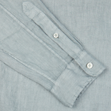 Close-up of a Xacus Sage Green Washed Linen Legacy Shirt cuff with two white buttons.