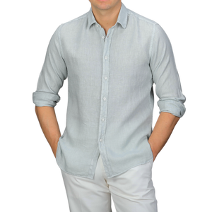 A person wearing the Xacus Sage Green Washed Linen Legacy Shirt with rolled-up sleeves and white pants, showcasing a stylish cut-away collar against a plain background.