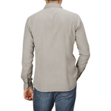 A person is standing with their back to the camera, wearing a Washed Beige Mussola Cotton Tailor Fit Shirt from Xacus and blue jeans.