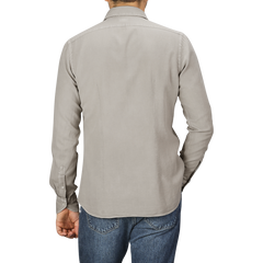 A person is standing with their back to the camera, wearing a Washed Beige Mussola Cotton Tailor Fit Shirt from Xacus and blue jeans.