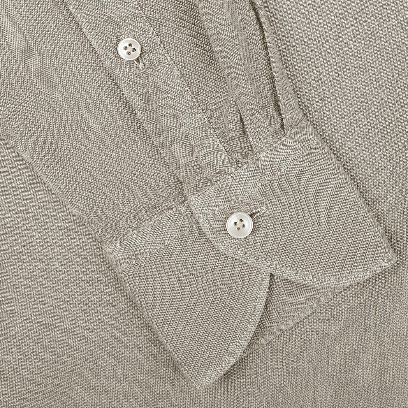 Close-up of a washed beige Mussola cotton Tailor Fit long-sleeve casual shirt cuff by Xacus, featuring white buttons and visible stitching details.