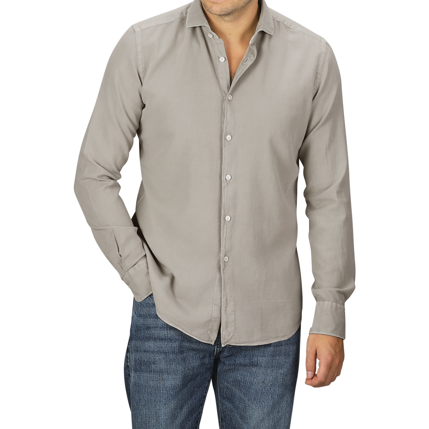 A person in a Washed Beige Mussola Cotton Tailor Fit Shirt by Xacus with the top button undone and slim fit blue jeans, posing with one hand in the pocket and the other by their side.