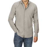 A person in a Washed Beige Mussola Cotton Tailor Fit Shirt by Xacus with the top button undone and slim fit blue jeans, posing with one hand in the pocket and the other by their side.