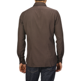 A person wearing a Washed Brown Mussola Cotton Tailor Fit Shirt by Xacus and blue jeans is shown from the back against a gray background.