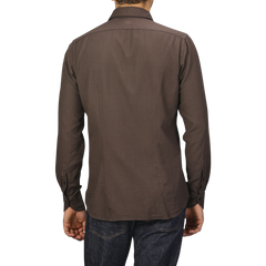 A person wearing a Washed Brown Mussola Cotton Tailor Fit Shirt by Xacus and blue jeans is shown from the back against a gray background.