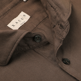 Close-up of the washed brown collar of the Xacus Washed Brown Mussola Cotton Tailor Fit Shirt, showcasing two black buttons and a tag that reads "Xacus Made in Italy.