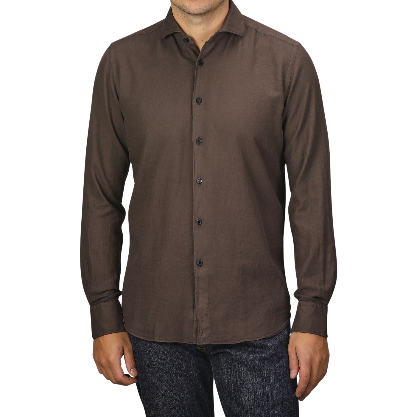 A person wearing a Washed Brown Mussola Cotton Tailor Fit Shirt by Xacus and dark jeans stands against a plain background.