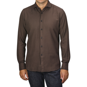 A person wearing a Washed Brown Mussola Cotton Tailor Fit Shirt by Xacus and dark jeans stands against a plain background.