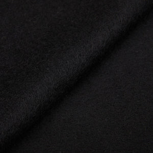 A close up image of a Yacaia black superfine merino wool scarf with fringed endings.
