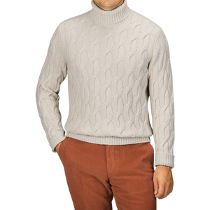 A person wearing an Ecru Beige Wool Cable Knit Rollneck from Zanone and rust-colored pants stands against a plain background. Face is not visible.