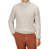 A person wearing an Ecru Beige Wool Cable Knit Rollneck from Zanone and rust-colored pants stands against a plain background. Face is not visible.