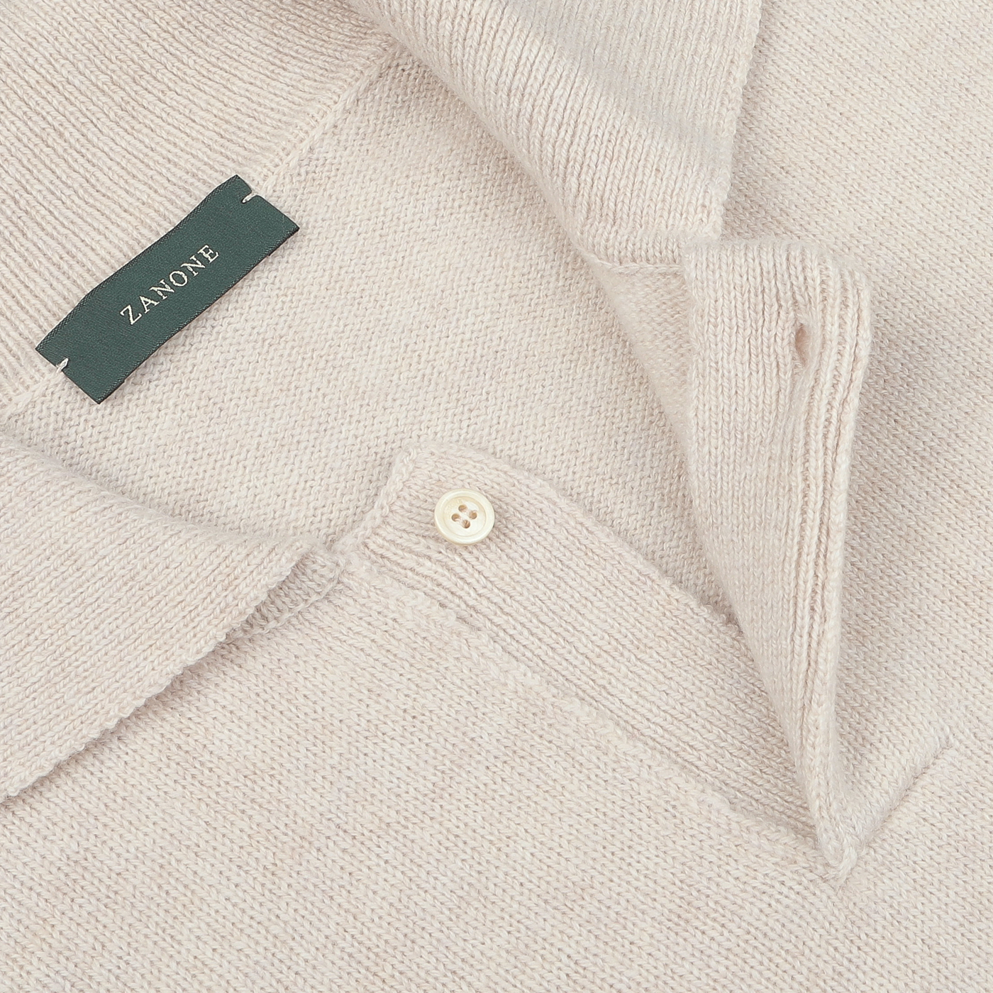 Close-up of an Ecru Beige Wool Winter LS Polo Shirt with a collared neckline and a partially buttoned front. This long-sleeve polo shirt, made from pure virgin wool, features a green label that reads "Zanone".