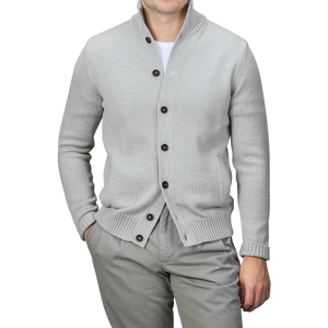 A person elegantly wears the Light Grey Merino Wool Button Cardigan by Zanone, draped over a white shirt and gray pants, with hands casually tucked in their pockets.