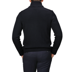 A person in a navy blue button cardigan made of merino wool from Zanone, shown from the back, stands against a gray background. Subtle sophistication meets timeless style with this chic ensemble.