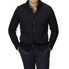 A person in a Zanone Navy Blue Merino Wool Button Cardigan, styled over a dark shirt and pants with hands casually tucked in pockets, stands against a gray background.