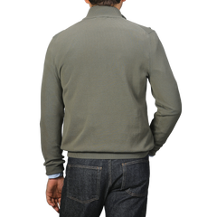 A man in a gray jacket and dark jeans, viewed from the back on a plain background, subtly contrasts with the Zanone Olive Green Crepe Cotton 1/4 Zip Sweater layered underneath.