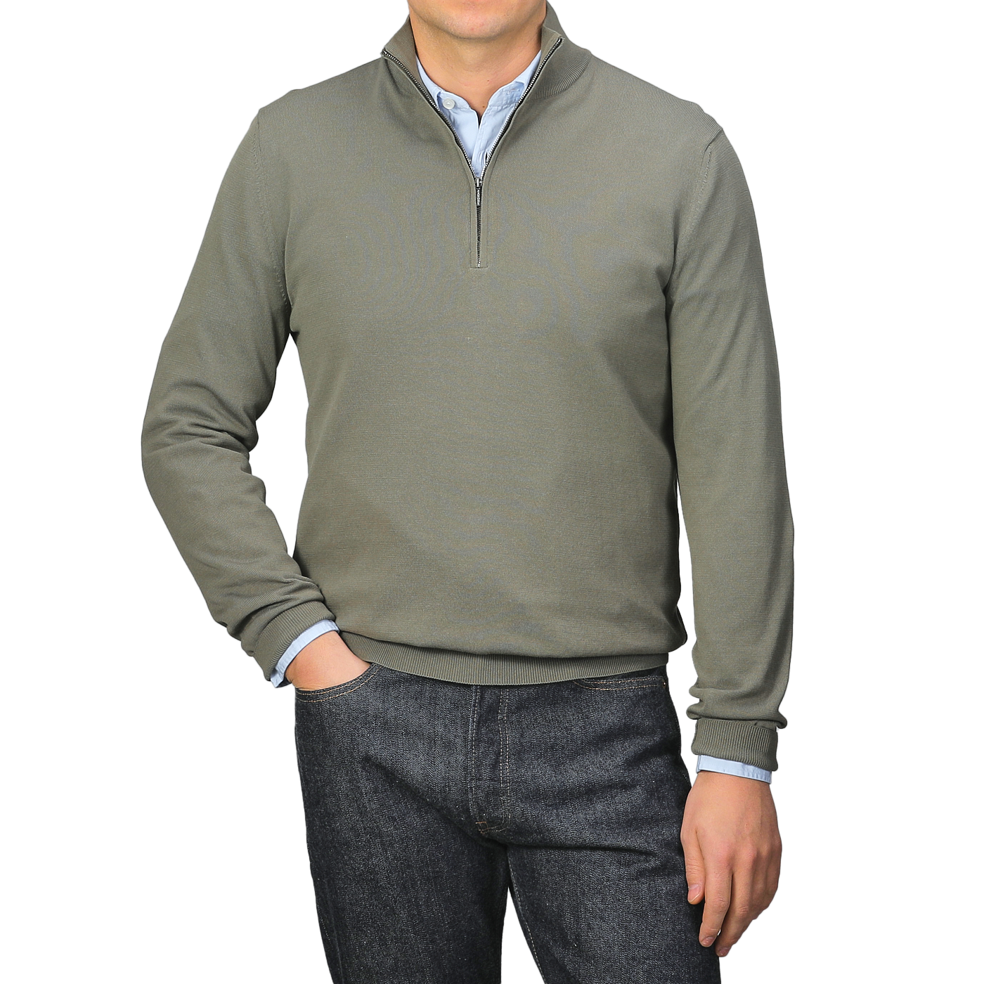 Dressed in an Olive Green Crepe Cotton 1/4 Zip Sweater by Zanone over a blue shirt and dark jeans, a person exudes effortless style, with one hand in their pocket while the other hangs by their side.