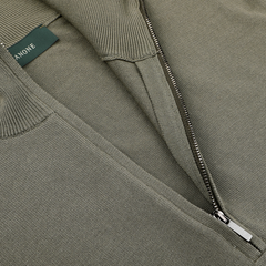 Close-up of a Zanone olive green Crepe Cotton 1/4 zip sweater featuring a ribbed texture and partially opened metal zipper, revealing a green label with white text.