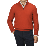 A man wearing a Zanone Rust Red Wool Quarter Zip Sweater over a white shirt and navy trousers with one hand in his pocket.