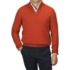 A man wearing a Zanone Rust Red Wool Quarter Zip Sweater over a white shirt and navy trousers with one hand in his pocket.