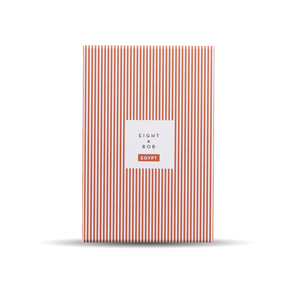 An orange and white striped Eight Bob notebook on a black background with a unique scent.