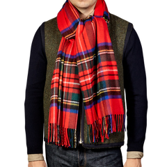 A person wearing a luxurious Red Checked Royal Stewart Cashmere Scarf by Johnstons Of Elgin over a dark shirt and vest.