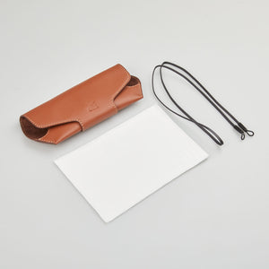 A Lunettes Alf brown leather case holding a notepad and paper with Brown Tortoise A22.15.006 Sunglasses.