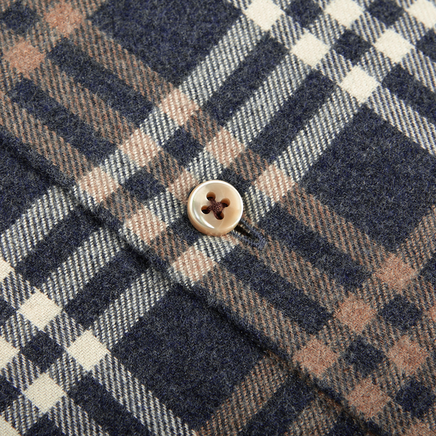 A detailed view of a button on the Blue Checked Cotton Flannel Slimline Shirt by Stenströms, featuring intersecting lines in beige, brown, and blue on brushed cotton twill.