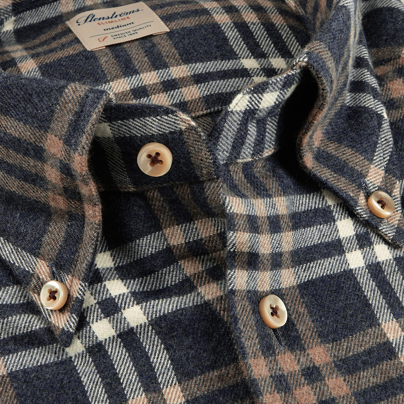 Close-up of the Stenströms Blue Checked Cotton Flannel Slimline Shirt with a brown plaid pattern and white and beige buttons. Made from brushed cotton twill, the shirt includes a visible brand and size tag.